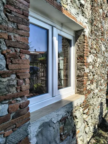 Finestra 2 ante in bianco su muratura in pietra, con davanzale